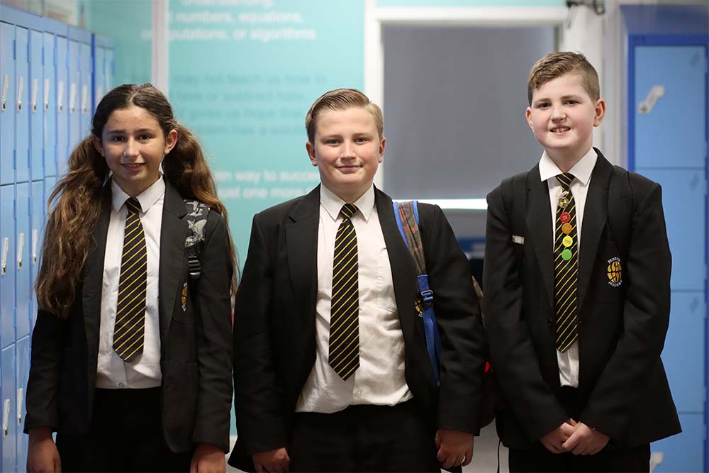 Three students walking down a corridor at Penrice Academy.